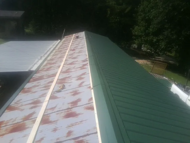 Old rusted panels beside newly installed green metal roofing — Wind Damage Roof Repair by Roofing Brothers in Dagsboro
