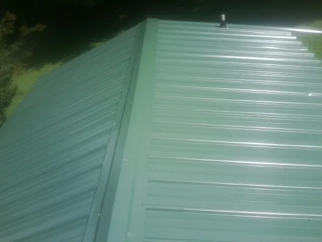 New green metal panels meeting at the ridge of a roof — Flat Roof Repair work by our crew in Dagsboro