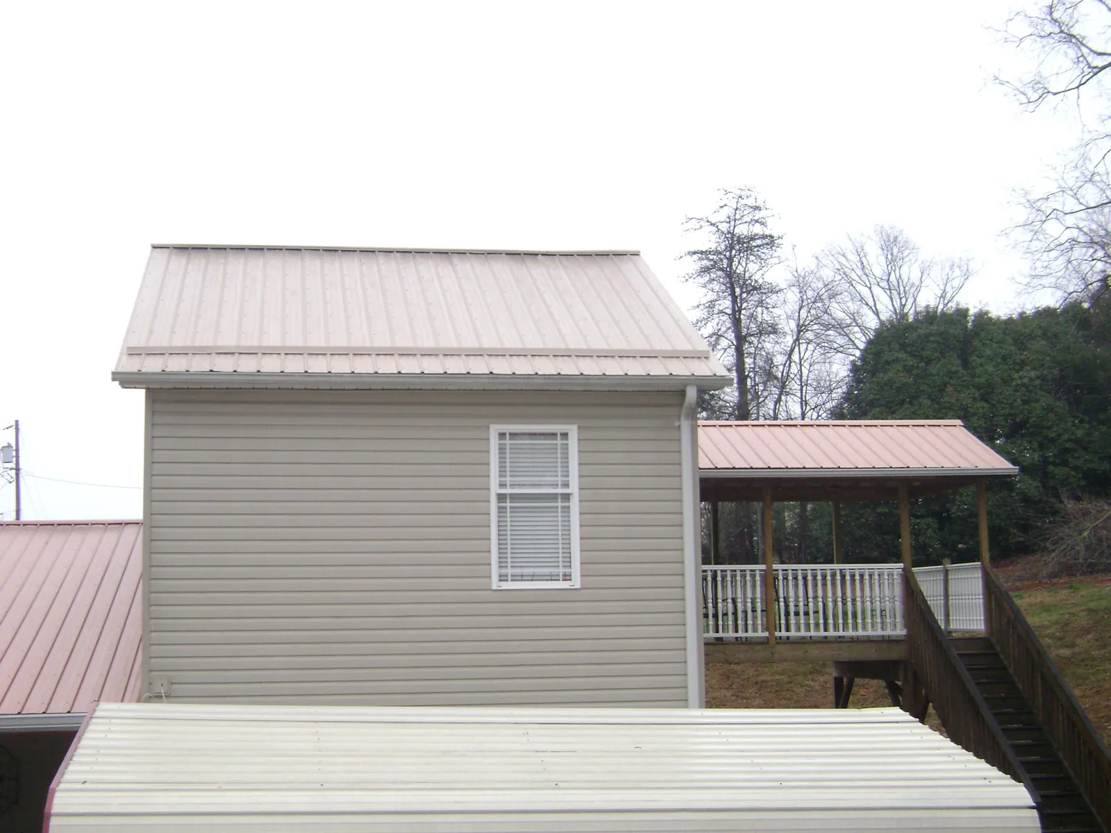 Tan metal roofs on a two story addition and attached porch, from a Roof Replacement job in Dagsboro