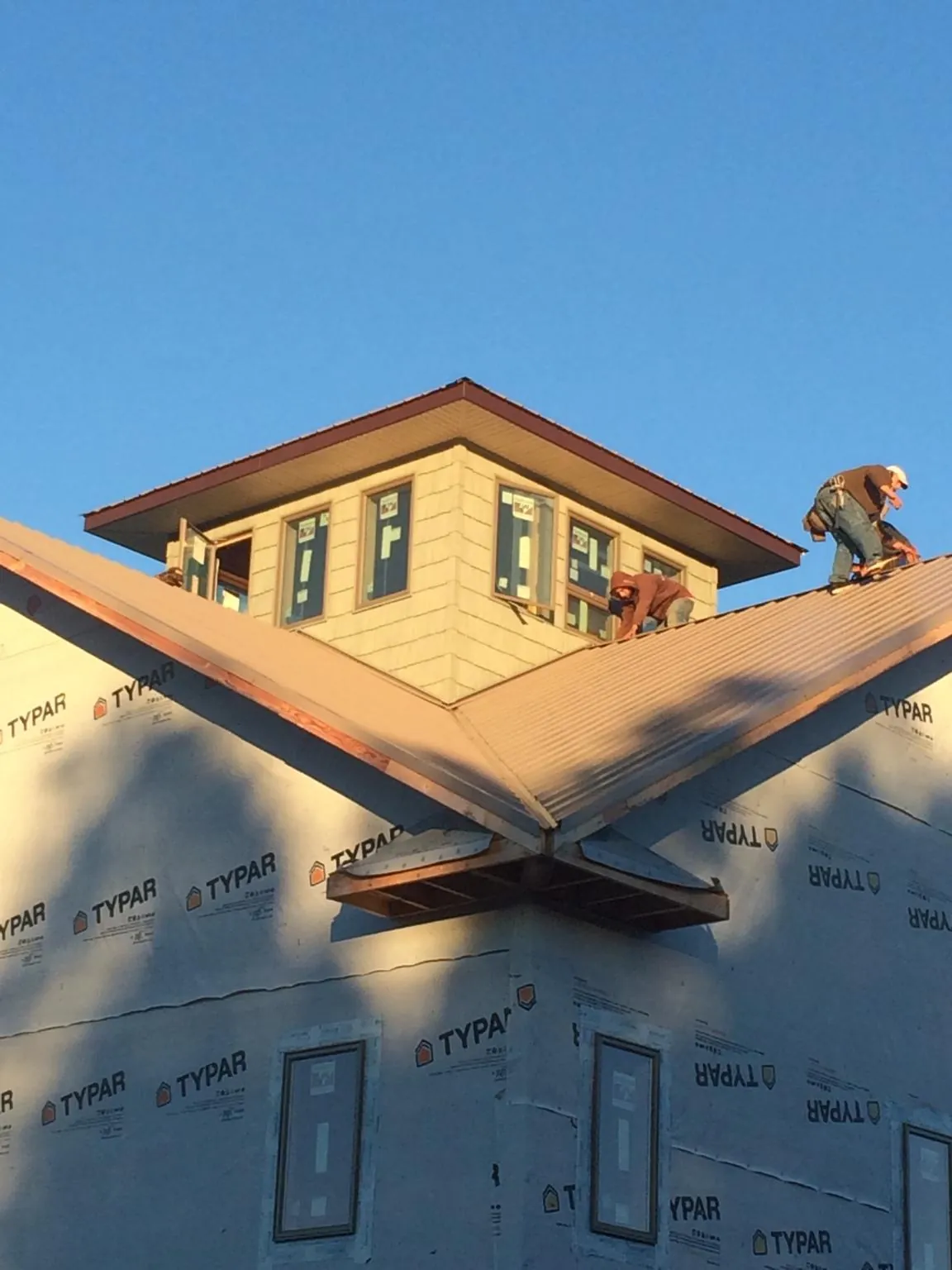 Roofers working around a rooftop cupola on a new metal roof at sunset — Roof Waterproofing in Dagsboro by Roofing Brothers